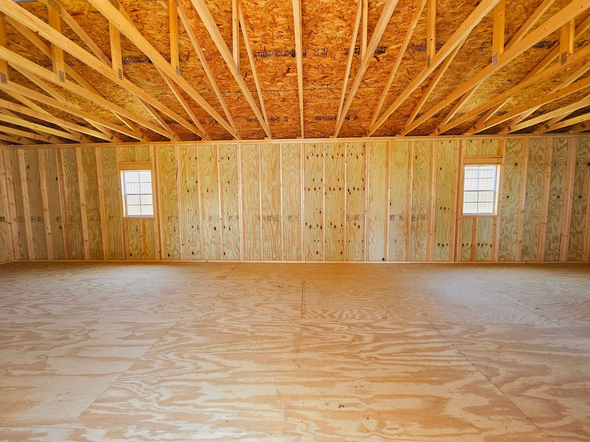 An empty room with a wooden floor and walls under construction.