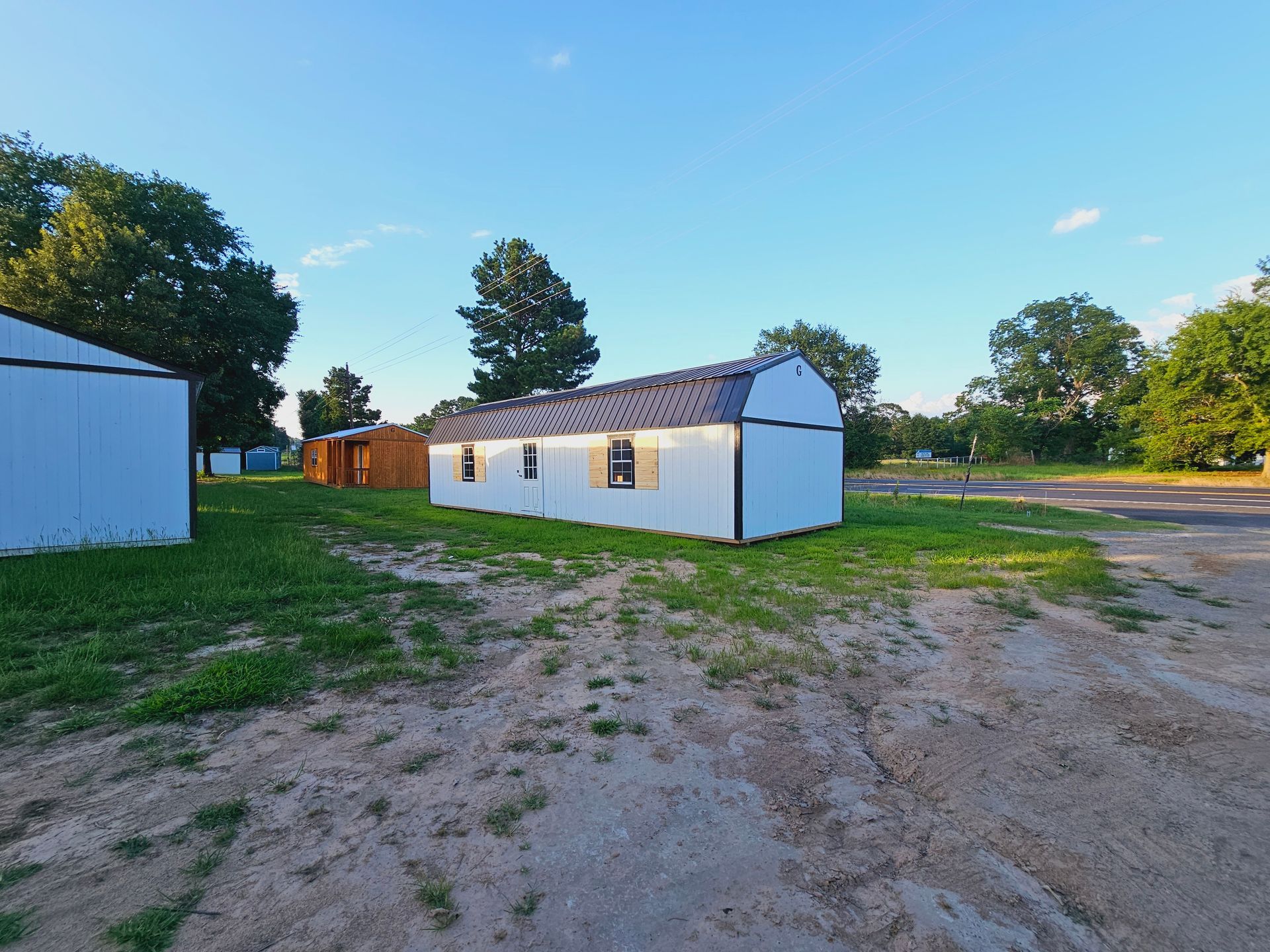 A white house is sitting in the middle of a dirt field.