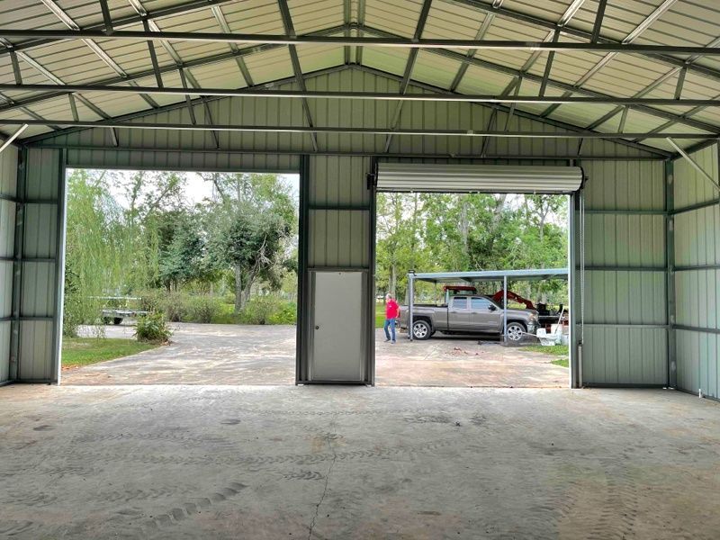 A truck is parked in a garage with the doors open.