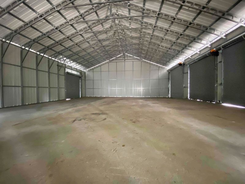 A large empty warehouse with a concrete floor and a metal roof.