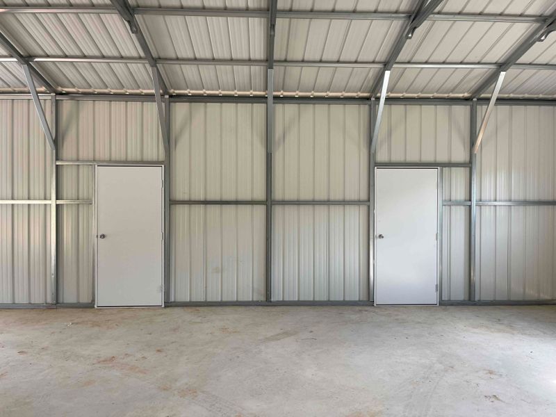 An empty metal building with two white doors and a concrete floor.