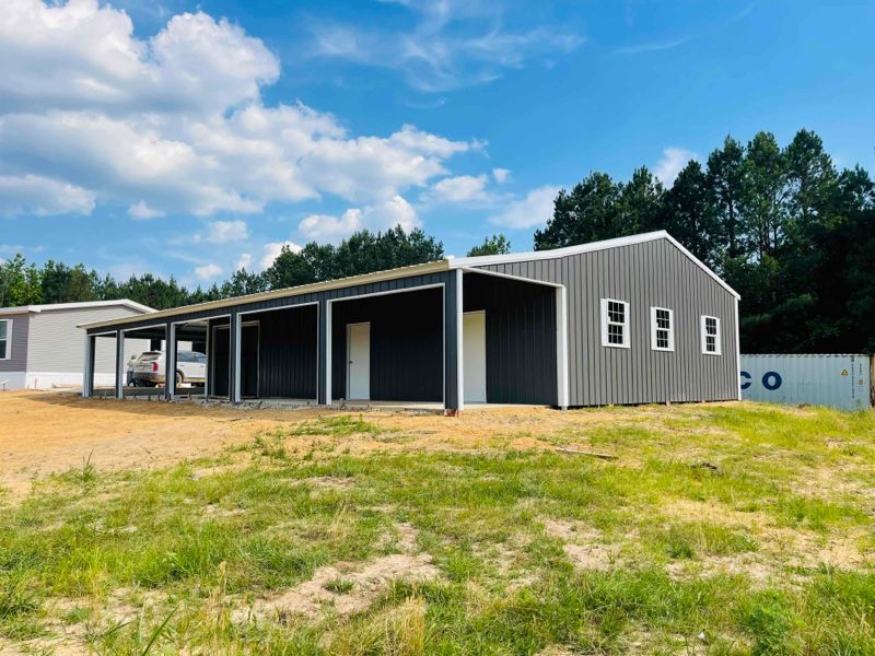 A large metal building is sitting in the middle of a grassy field.