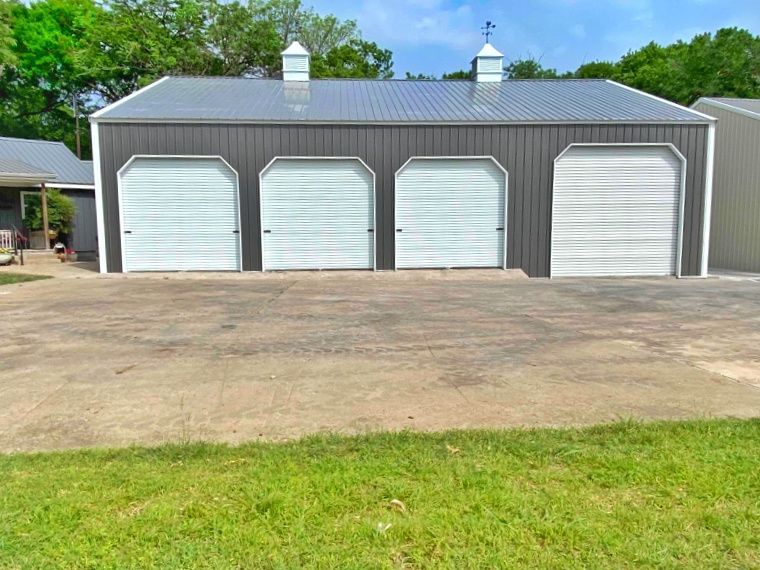 A garage with three white garage doors and a gray roof