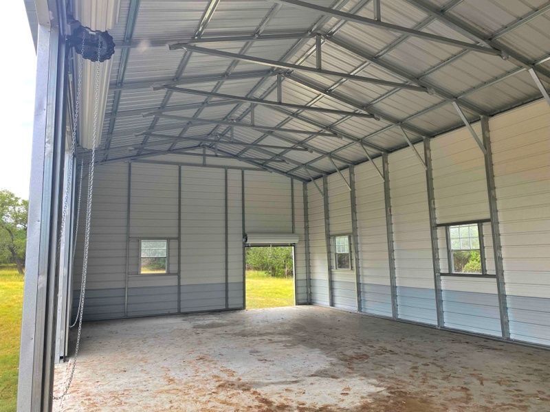 The inside of a metal building with a sliding door and windows.