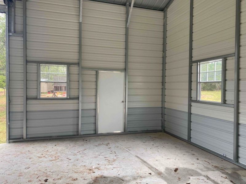 An empty garage with a door and two windows.
