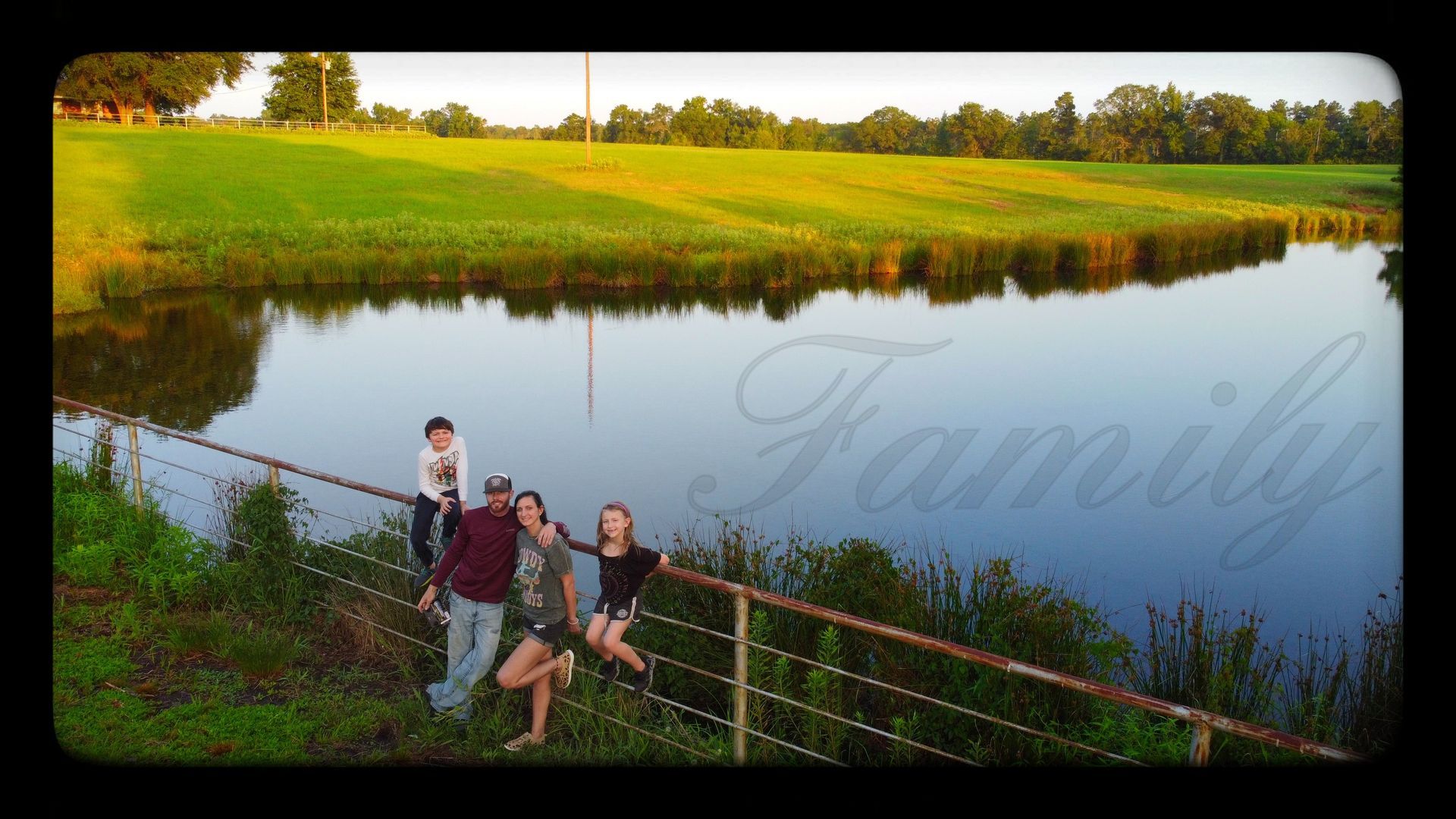 A family standing on a fence overlooking a lake with the word family on the bottom
