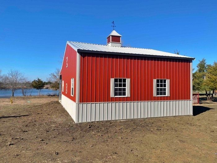 A red and white barn with a weather vane on top