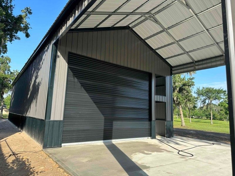 A large metal building with a garage door and a canopy.