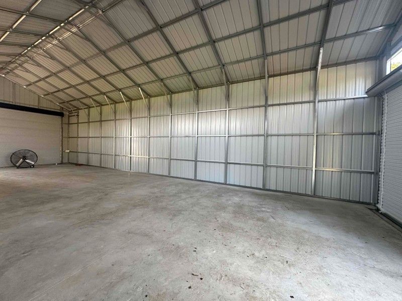 A large empty warehouse with a fan in the middle of it.