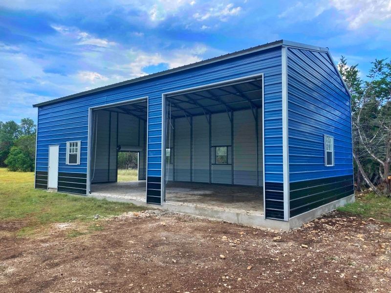 A blue metal garage with two doors is sitting on top of a dirt field.