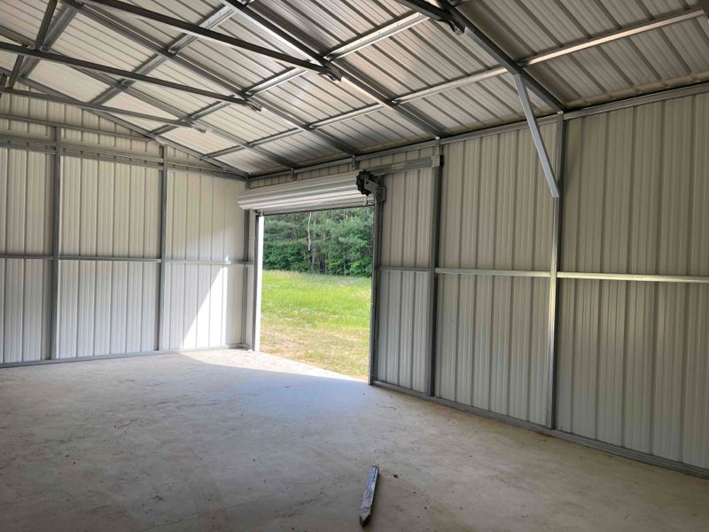 The inside of a metal garage with a garage door open.