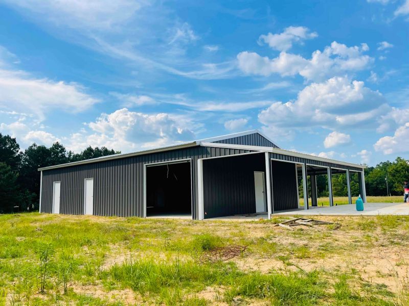A large metal building is sitting in the middle of a grassy field.