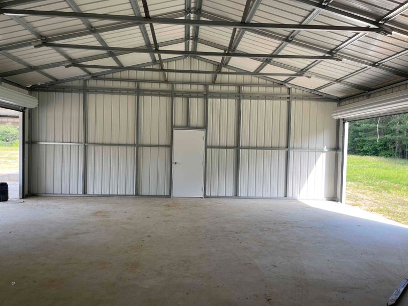 A large empty metal building with a roof and a door.