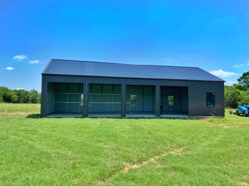 A large metal building is sitting in the middle of a grassy field.