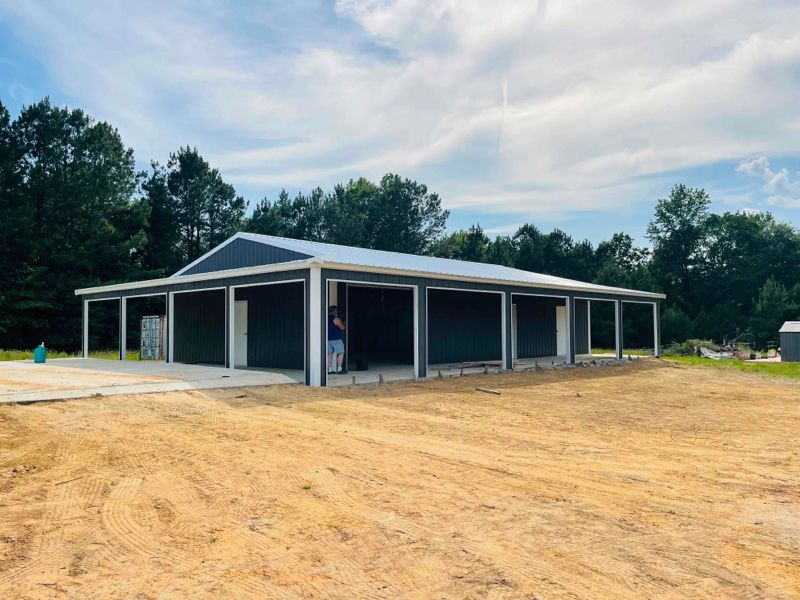 A large metal building is sitting in the middle of a dirt field.
