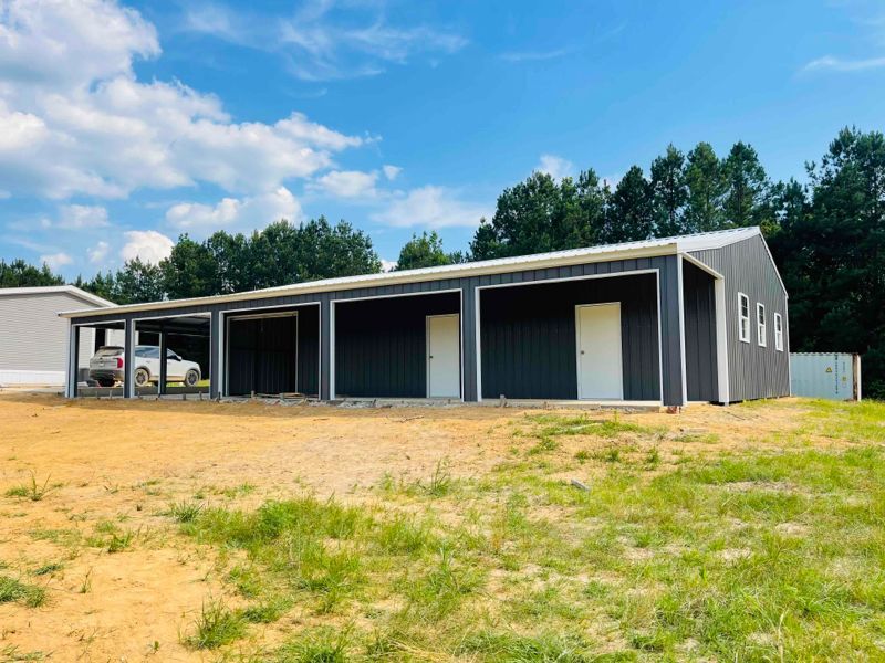 A large metal building is sitting in the middle of a grassy field.