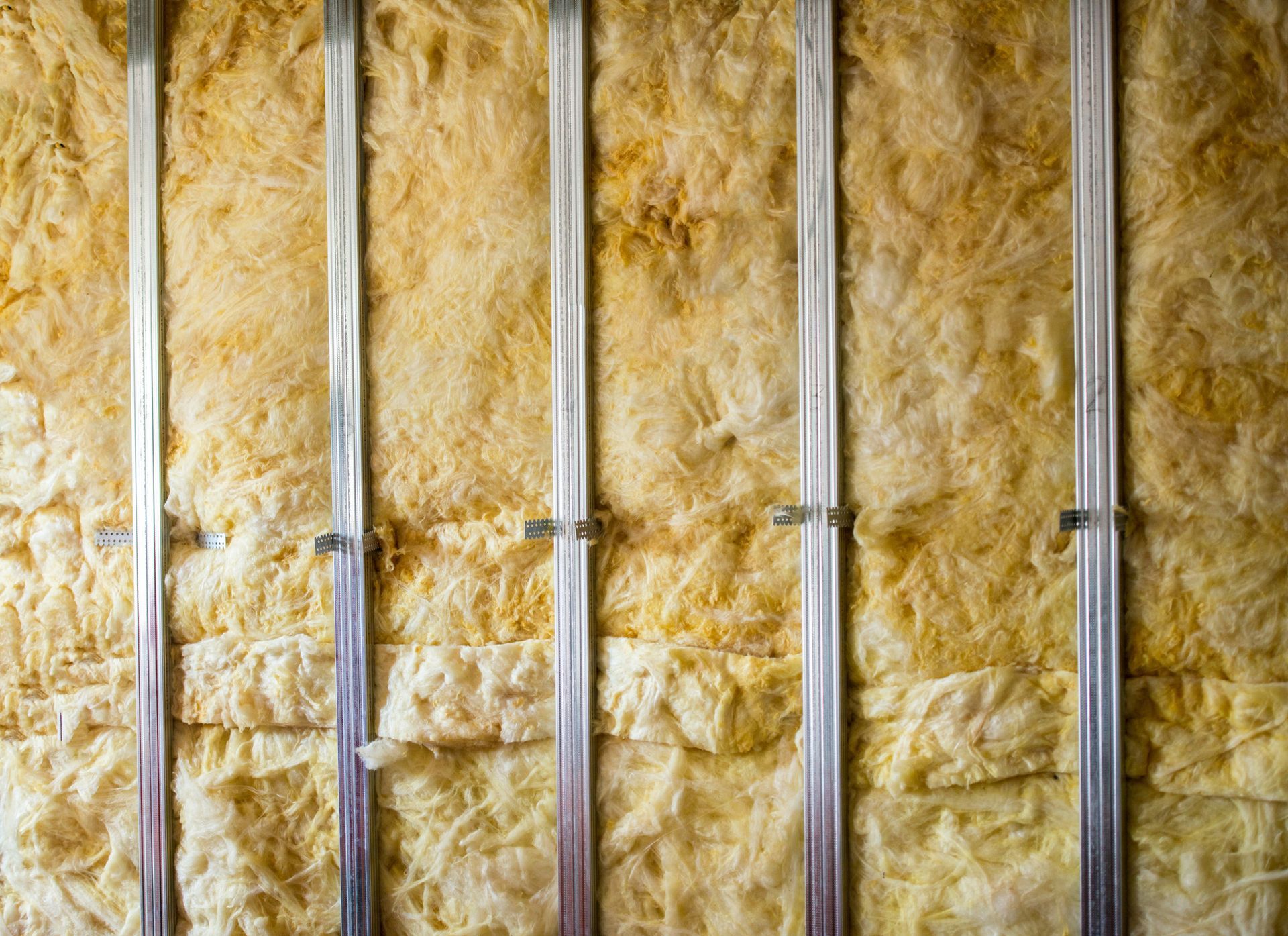 A close up of a wall with insulation and metal frames.