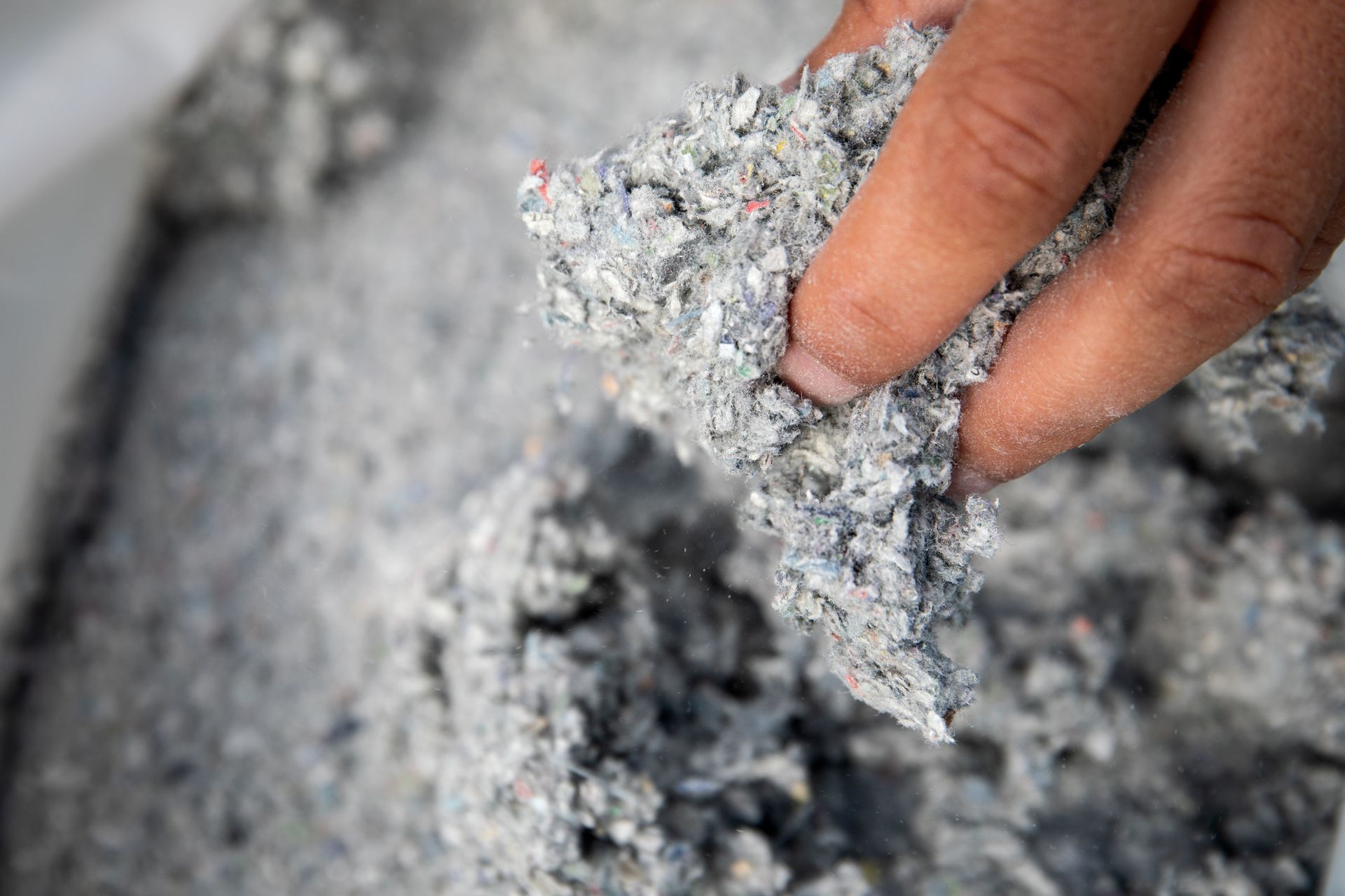 A person is holding a piece of concrete in their hand.