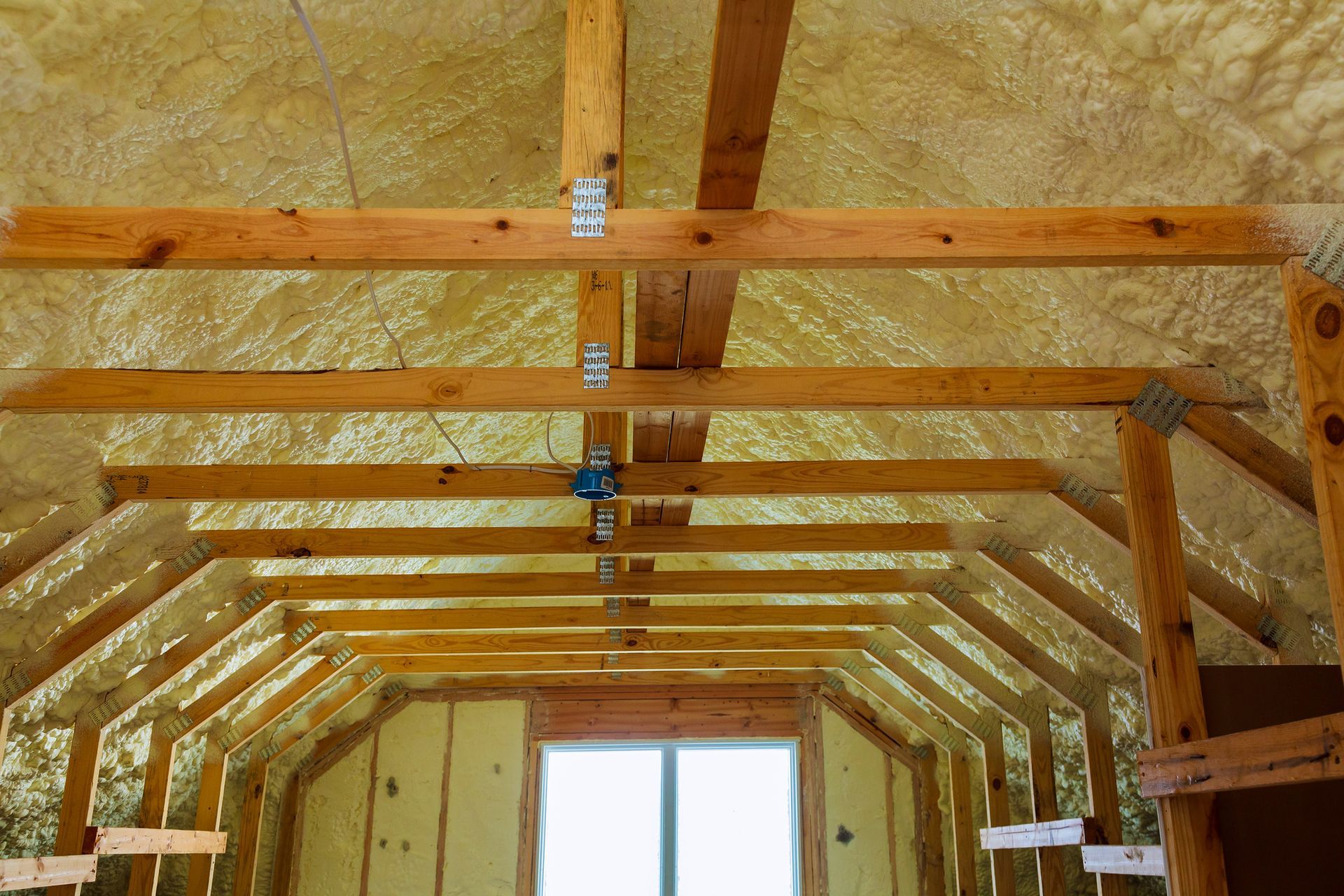 The ceiling of an attic with wooden beams and insulation.