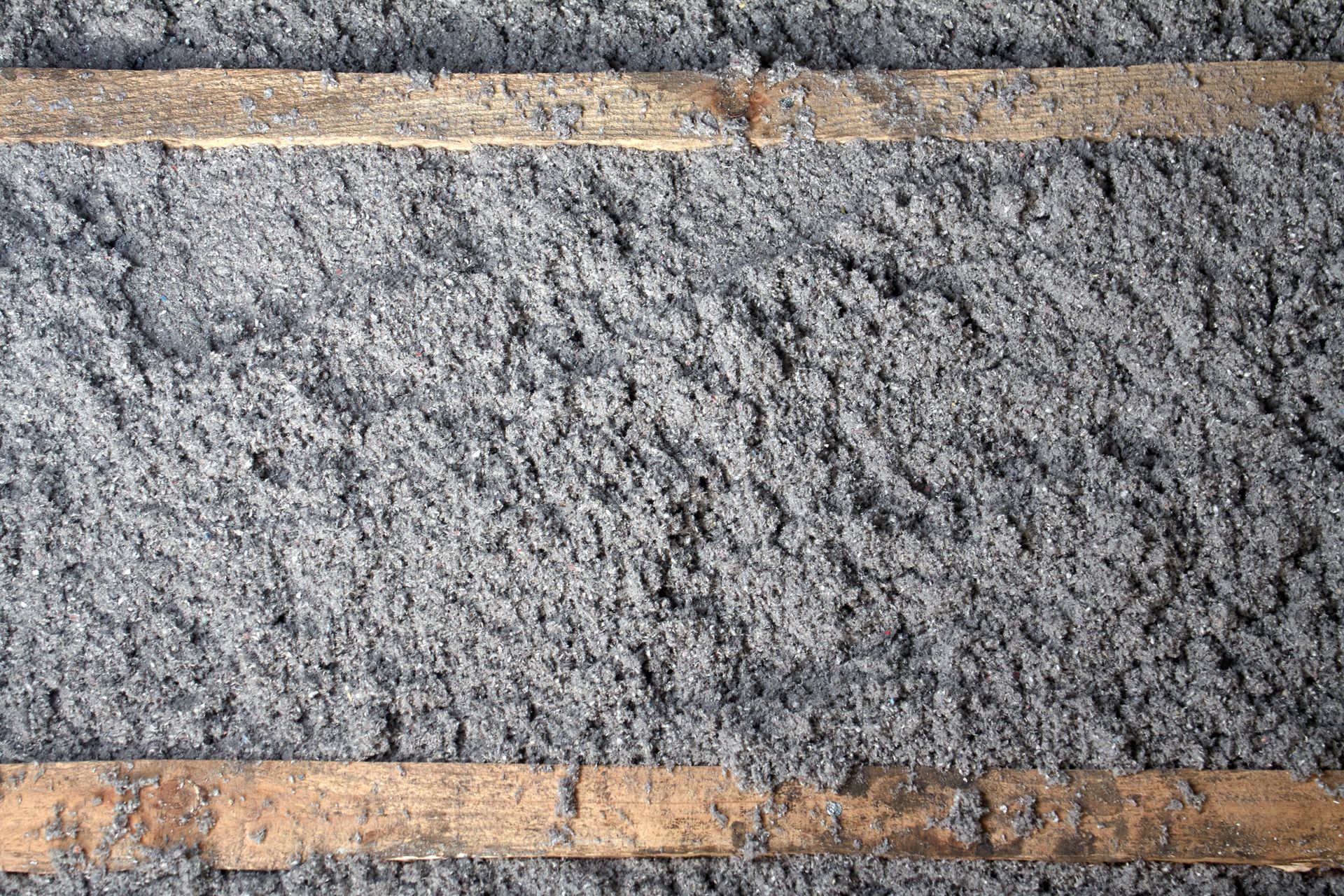 A close up of a concrete wall with wooden beams.