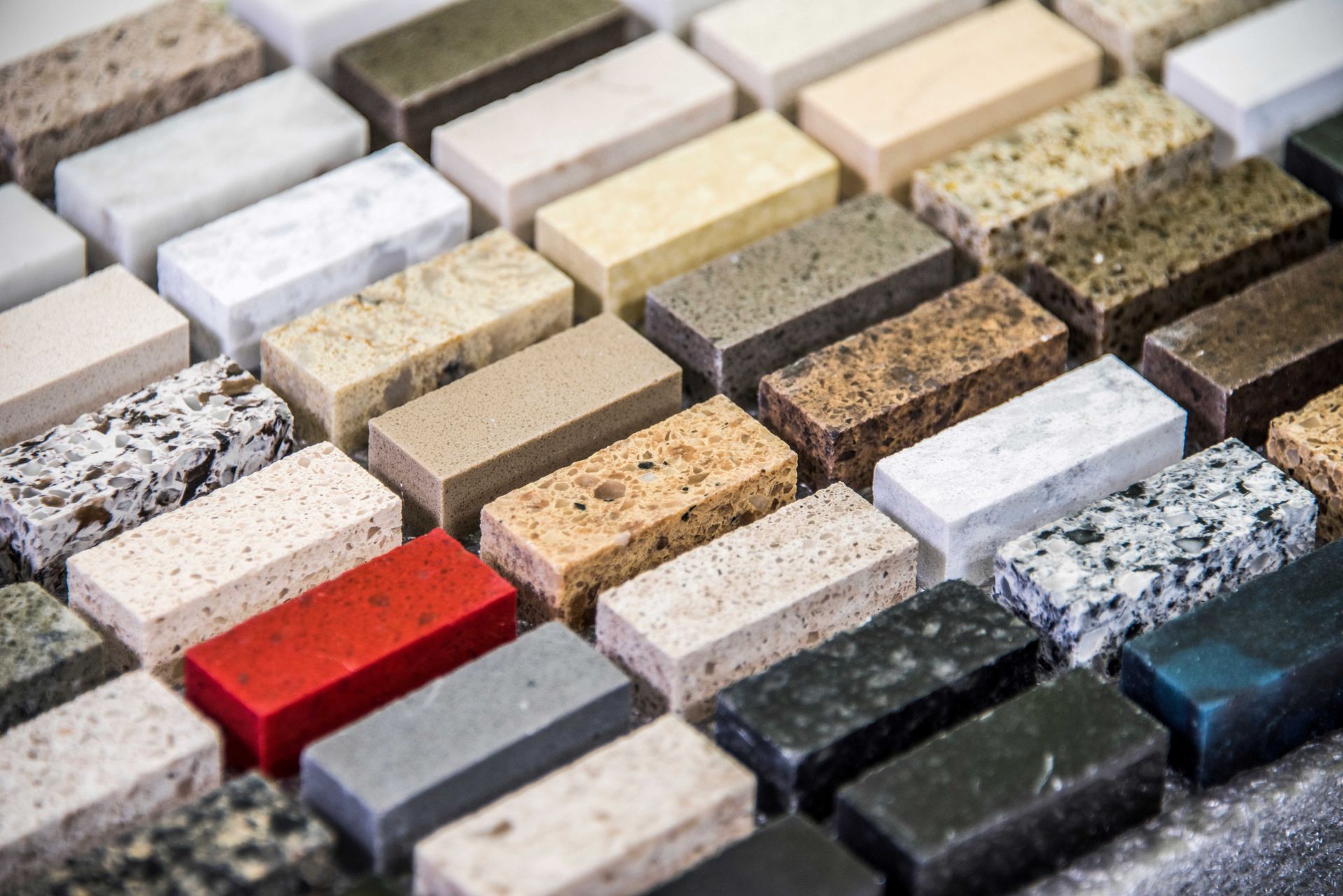 Assorted rectangular stone tiles in various colors and textures arranged in rows Assorted rectangular stone tiles in various colors and textures arranged in rows