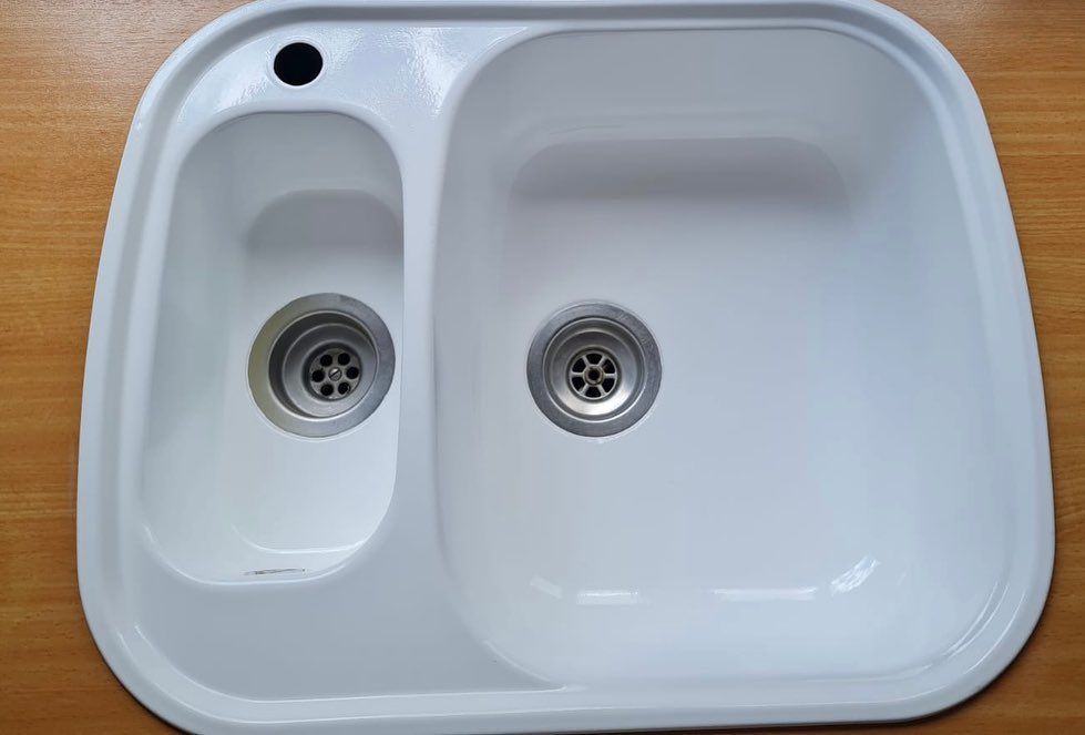A white kitchen sink with two drains and a hole in the middle