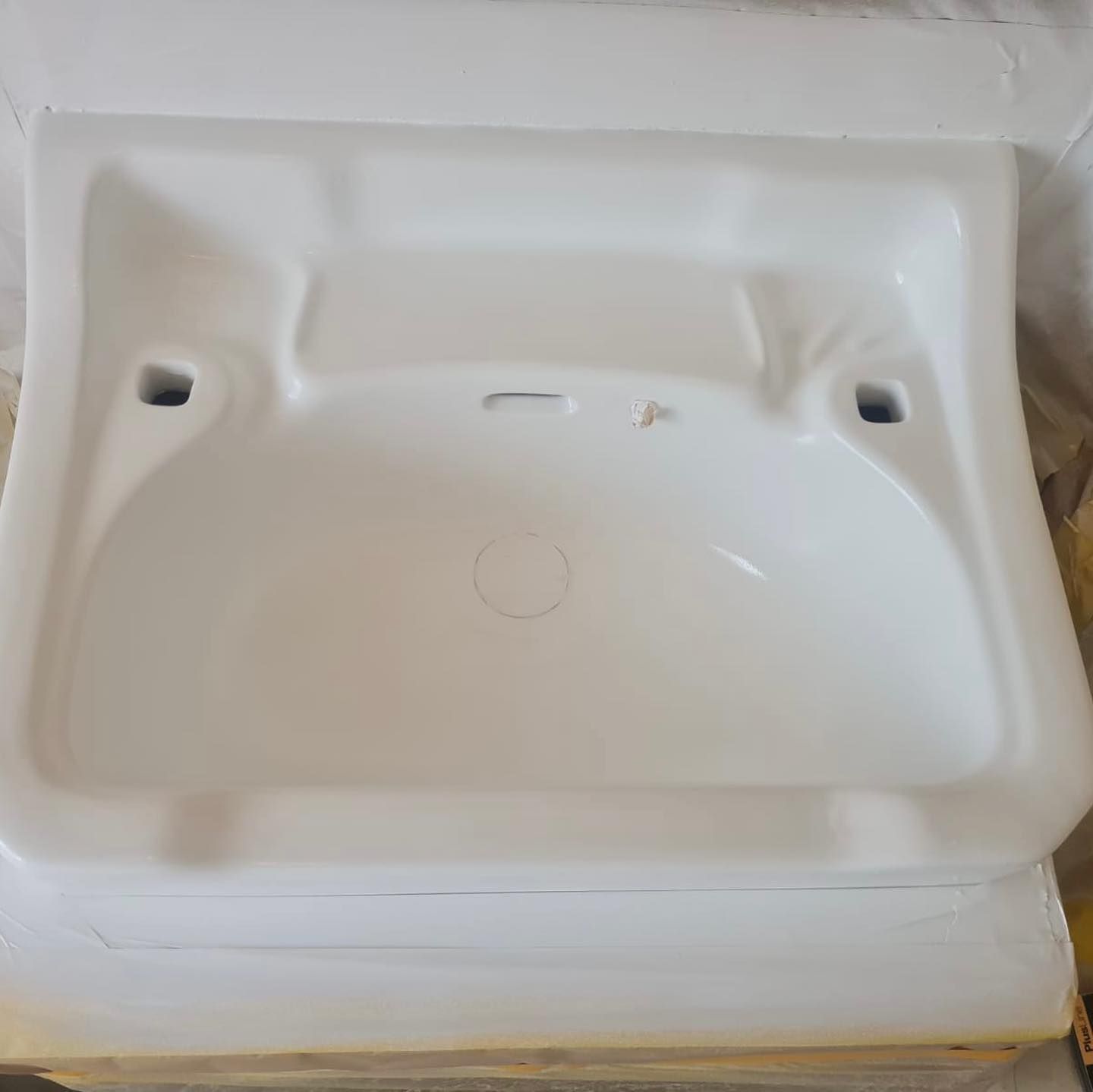 A white sink is sitting on top of a wooden table.