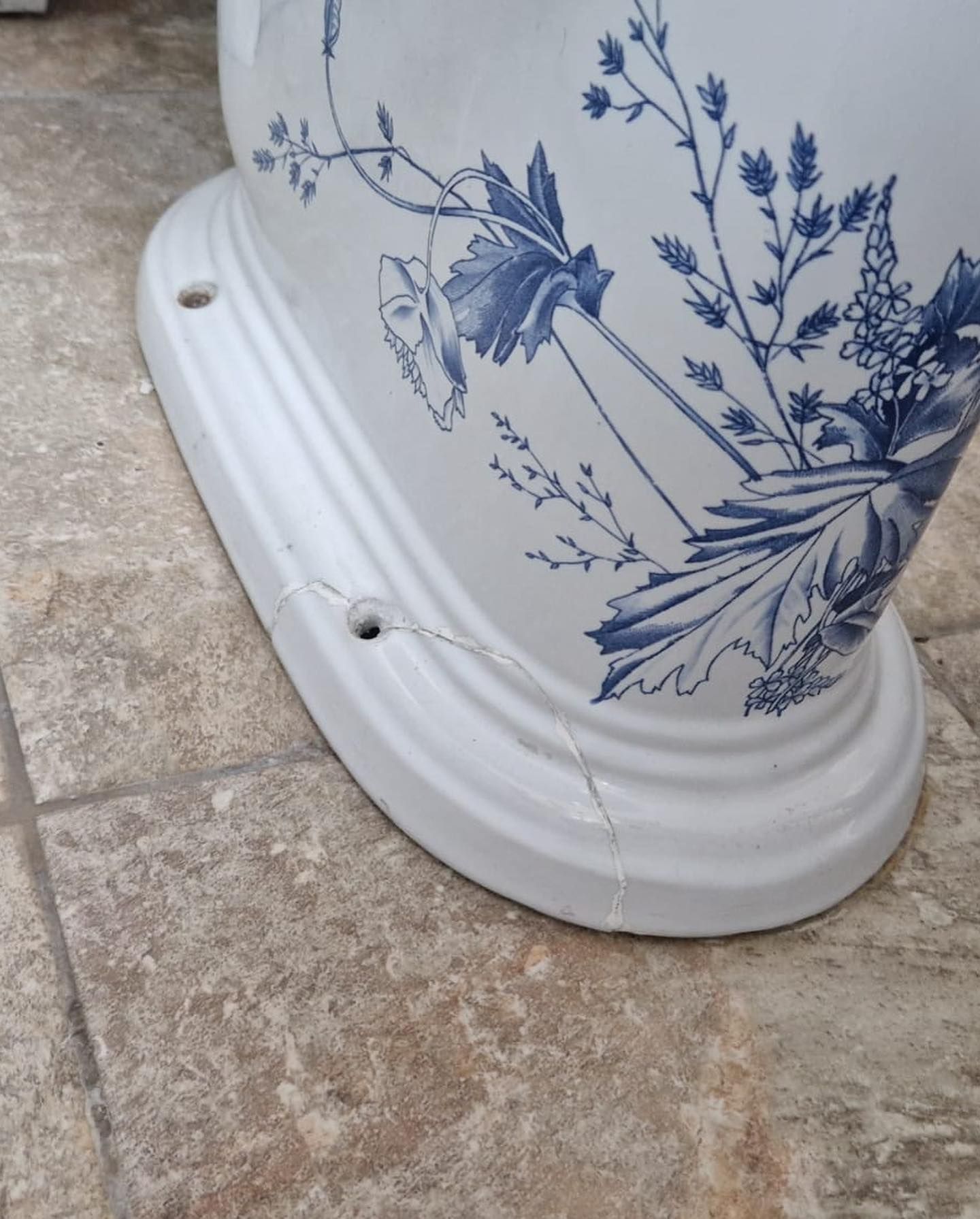 A blue and white toilet with a cracked base