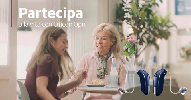 Due donne chiacchierano a un tavolo, con apparecchi acustici in vista e la scritta