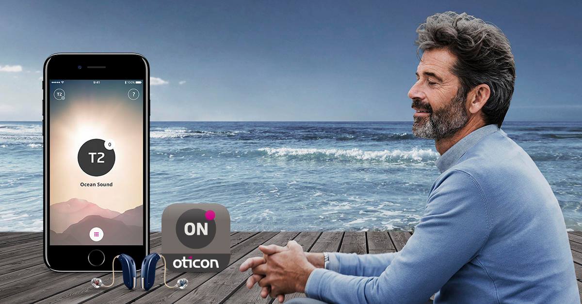 Un uomo su una spiaggia utilizza un'app per smartphone con un dispositivo indossabile sulla sabbia.