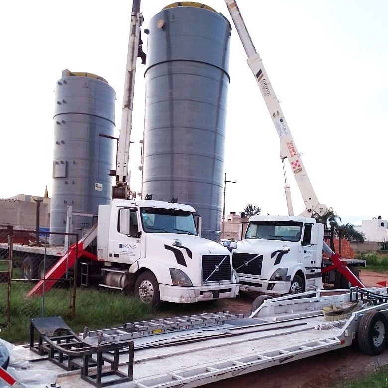 Dos grúas industriales realizando un izaje conjunto de unos tanques