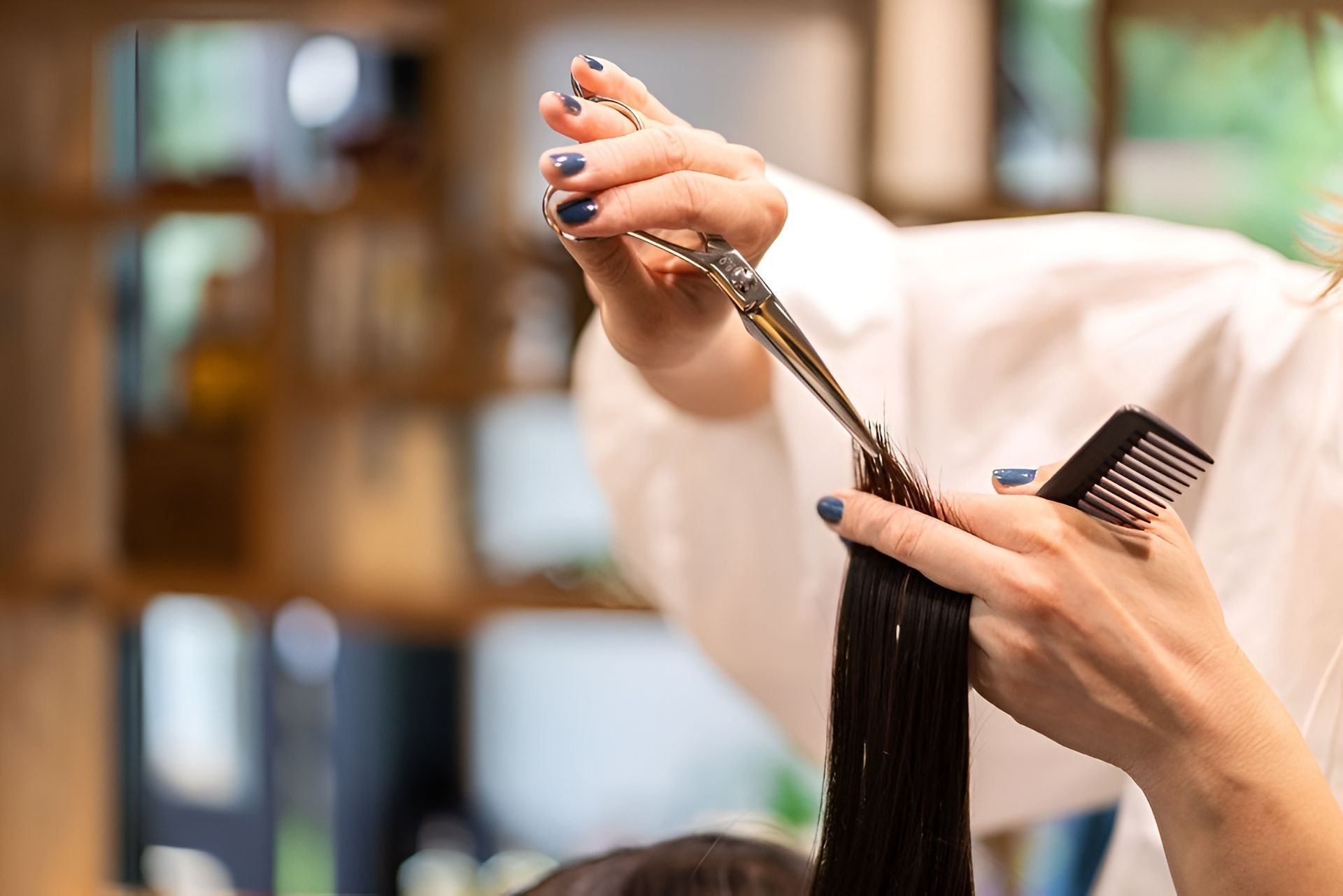 Hair Stylist Cutting a Client's Long, Dark Hair With Scissors and Comb in a Salon — Lavish Hair in Shepparton, VIC