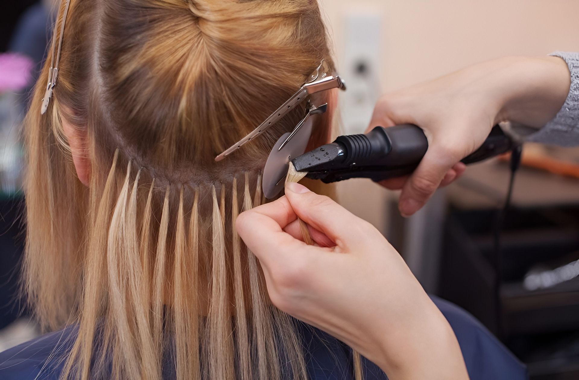 Hair Stylist Applying Blonde Hair Extensions Using a Tool — Lavish Hair in Shepparton, VIC