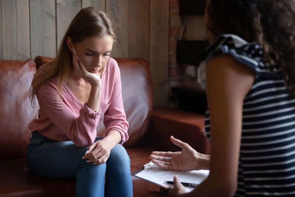 A Woman Is Sitting On A Couch Talking To Another Woman — Wegner Therapies In Pialba, QLD