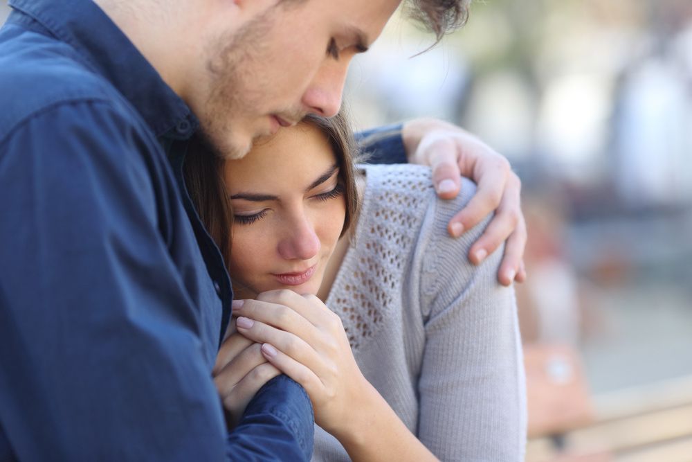A Man Is Comforting A Woman Who Is Sitting On A Bench — Wegner Therapies In Pialba, QLD
