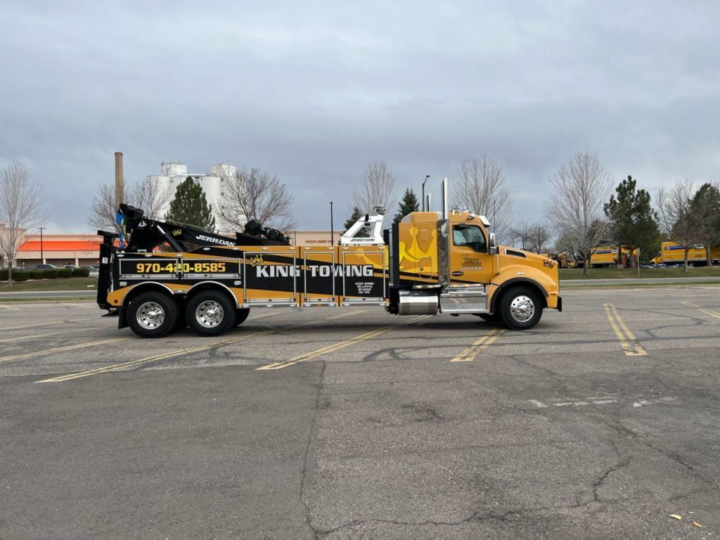 Yellow tow truck parked in an empty lot on a cloudy day