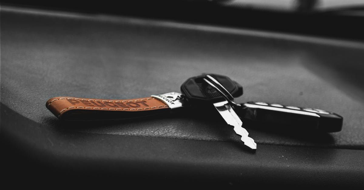 Car key with black fob and brown leather strap resting on a dark surface.