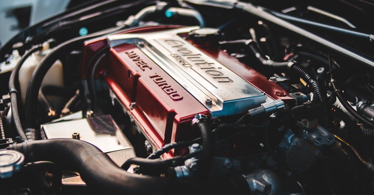 Close-up of a car engine bay with a red valve cover and surrounding black hoses and wiring
