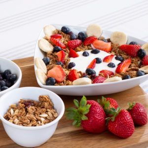 A bowl of granola with strawberries bananas blueberries and yogurt