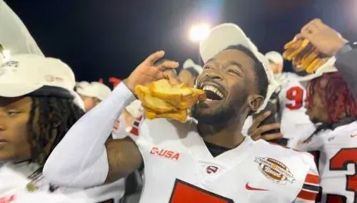 A football player is eating a hot dog on the field.