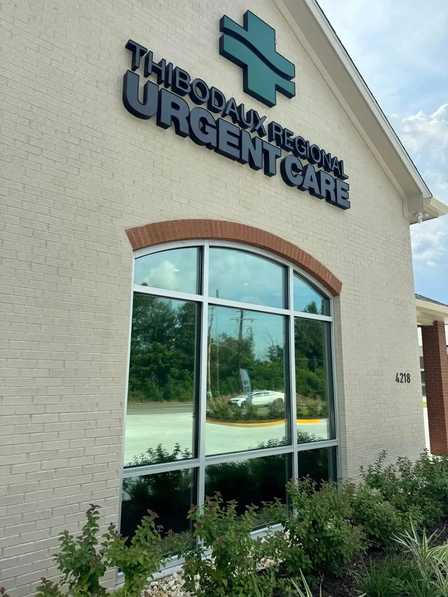 Exterior of Thibodaux Regional Urgent Care building with signage and large arched window.