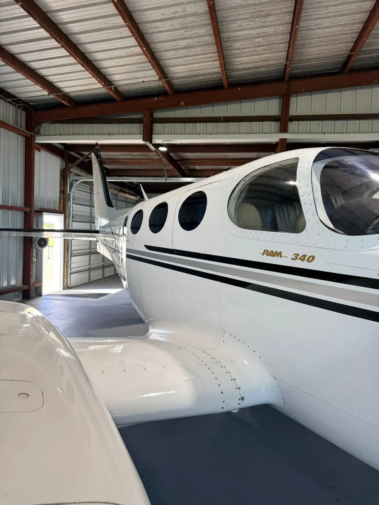 White airplane in a hangar, with black and gray stripes, and the words 