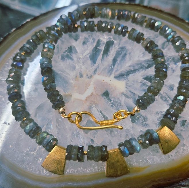 Labradorite gemstone necklace with gold clasp and accents, on an agate slice.