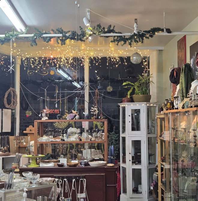 A shop interior with jewelry displays, lit by string lights and decorated for the holidays.