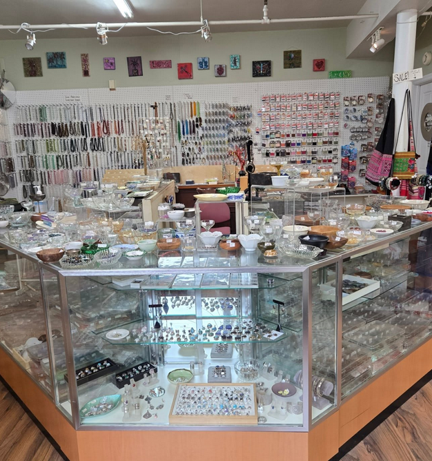 Jewelry store interior with glass display cases, filled with various items, and necklaces hanging on the back wall.