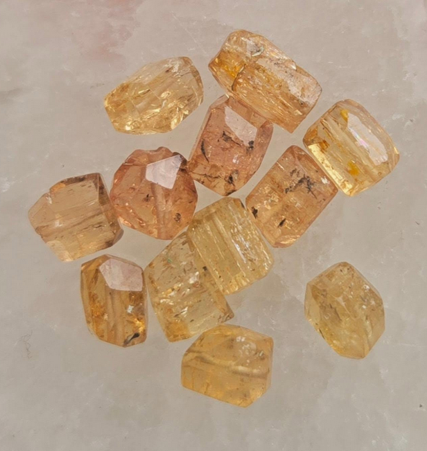 Loose, translucent, golden-yellow topaz crystals on a light-colored surface.