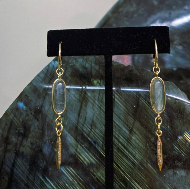 Gold drop earrings with blue-grey oval stone and dangling, gold, diamond-encrusted point.