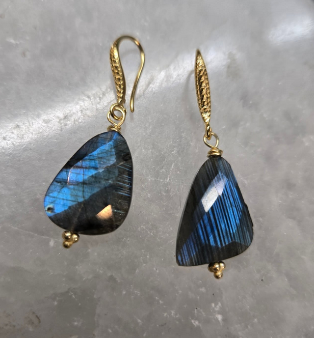 Gold earrings with teardrop-shaped blue labradorite stones against a white background.
