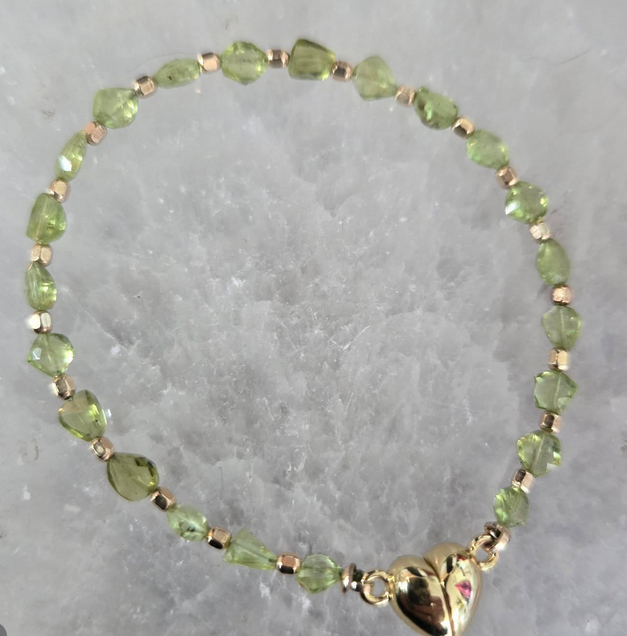 Green beaded bracelet with gold accents and heart-shaped clasp.