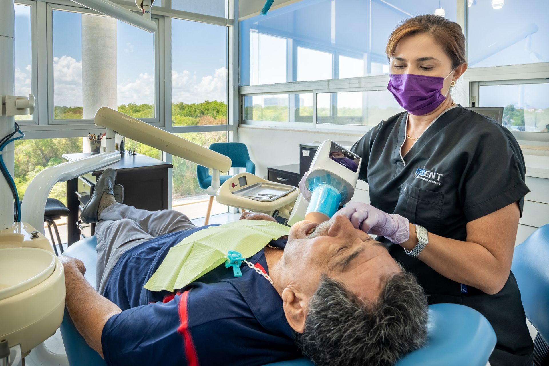 Dentista atendiendo a un paciente recostado en una clínica luminosa, 